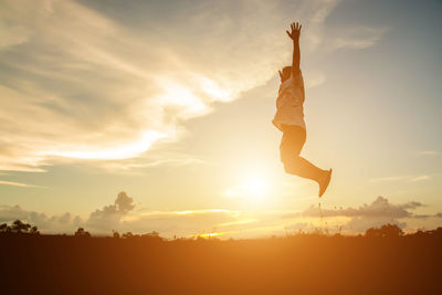 Silhouette man jumping against sky during sunset