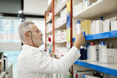 Pharmacist stacking medicines on shelf in pharmacy store
