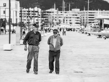 Rear view of men walking on street in city