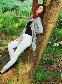 Woman with arms raised on tree trunk