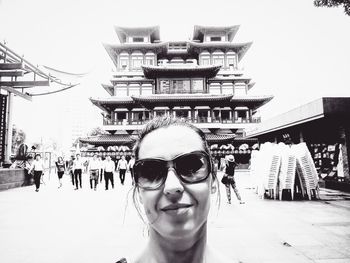 Portrait of smiling young woman against building