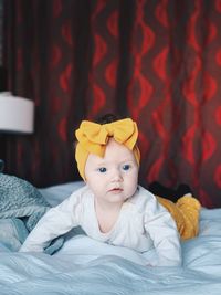 Portrait of baby girl lying on bed at home