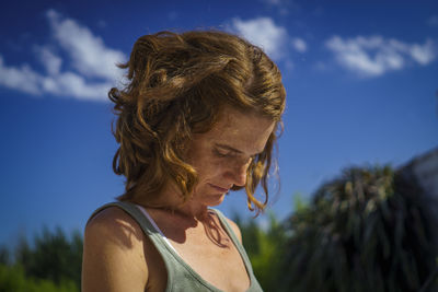 Low angle view of young woman standing against sky