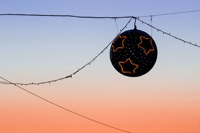 Low angle view of lighting equipment hanging against clear sky