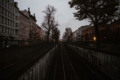 Railroad tracks in city against sky at dusk