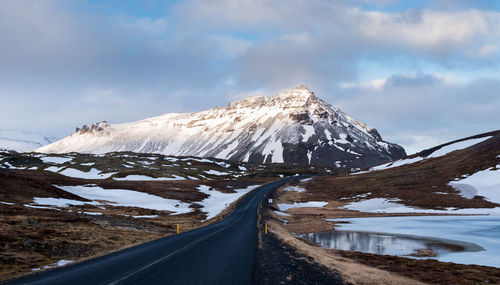 Typical icelandic snowy nature mountain landscape and empty road. 