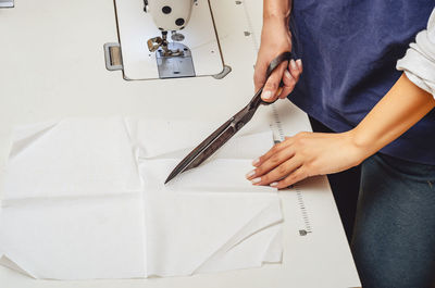 Dressmaker cuts white cloth with large knives