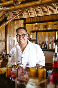 Portrait of happy bartender with eyeglasses at counter in resort