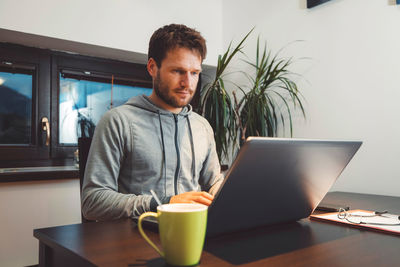 Young woman using laptop while sitting on table