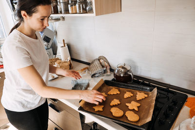 Woman cooking gingerbread. christmas homemade gingerbread biscuit at baking pan on home kitchen