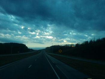 Empty road against cloudy sky