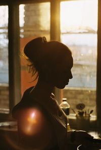 Girl standing in kitchen at home on sunny day