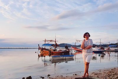 Rear view of woman standing at beach against sky