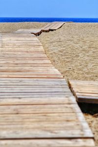 Boardwalk on beach against clear sky