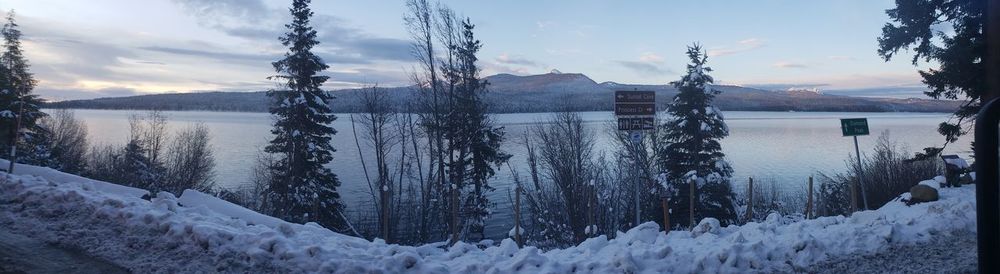 Scenic view of lake by snowcapped mountains against sky