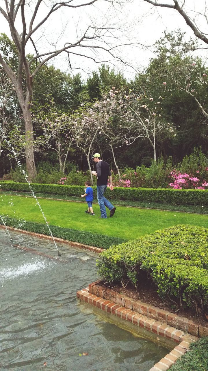 BOY PLAYING IN PARK AGAINST WATER IN POND