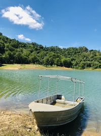 Boat moored on lake against sky