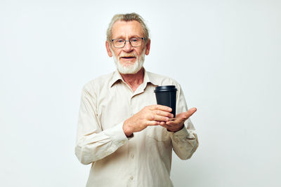 Portrait of young man using mobile phone while standing against white background