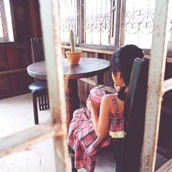 Rear view of girl having drink seen through window