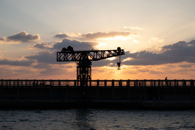 Silhouette pier over sea against sky during sunset