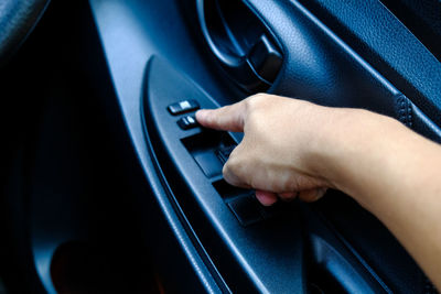 Cropped hand of person pressing button in car