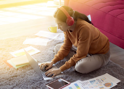 High angle view of woman using mobile phone while sitting on bed at home