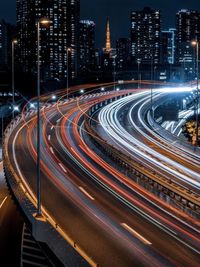 High angle view of light trails on road amidst buildings at night