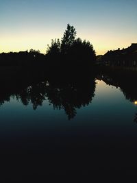 Reflection of silhouette trees in lake against sky at sunset