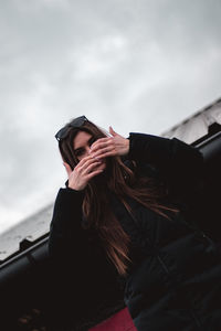 Portrait of woman holding umbrella against sky