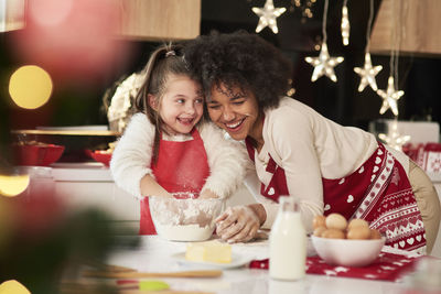 Smiling girl making food with mother at home