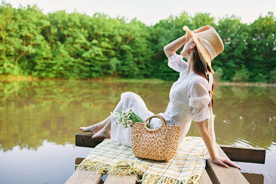 Rear view of woman sitting by lake