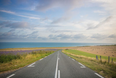 Empty road along landscape against sky