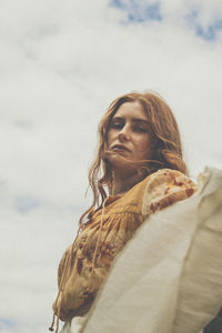 Low angle view of woman looking at camera against sky