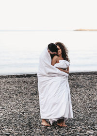 A couple in love spend the night at the sea, kissing and hugging on the beach covered with a blanket