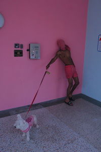 Side view of woman standing against pink wall