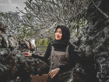 Young woman standing on rock against trees