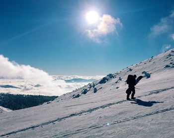 Woman walking on snow covered mountain against sky