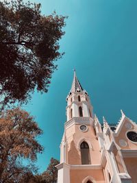 Low angle view of trees and building against sky