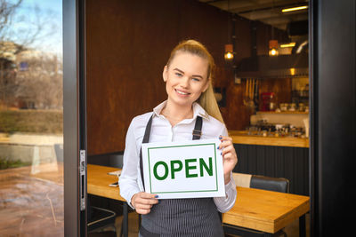 Portrait of a smiling young woman standing in restaurant