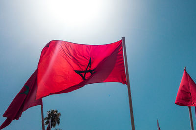 Low angle view of red flags against clear blue sky