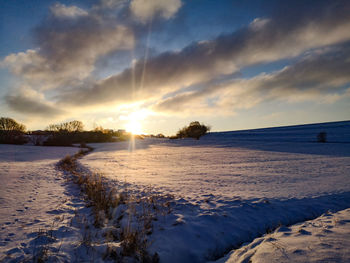 Scenic view of snow covered land against sky during sunset