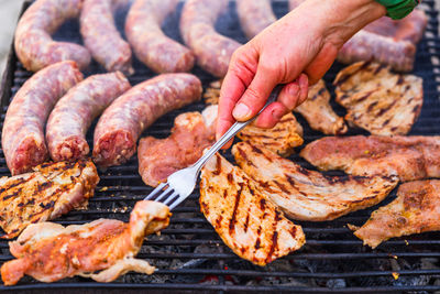 Cropped hand of person preparing food on barbecue grill