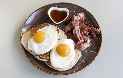 Delicious homemade breakfast with crispy bacon, eggs and pancakes