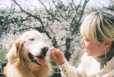 Portrait of woman with dog against trees