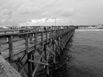 Pier on sea against cloudy sky