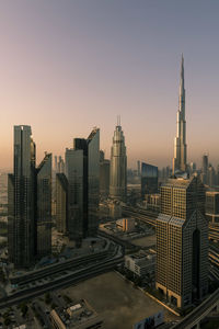 Modern buildings in city against sky during sunset