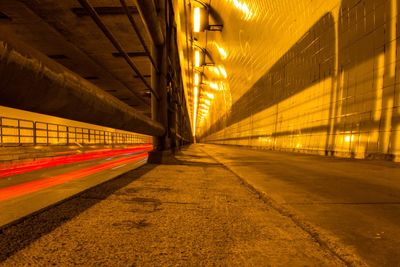 Walking path on the side of a tunnel for vehicles with light trails from vehicles 