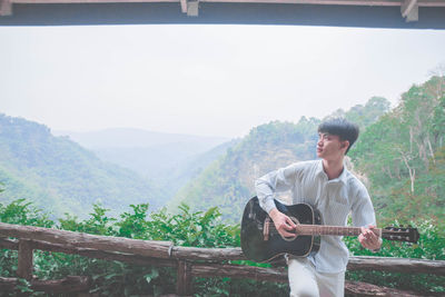 Side view of young man standing against mountain