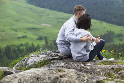 Rear view of couple sitting on rock