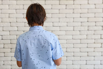 Rear view of man standing against white wall